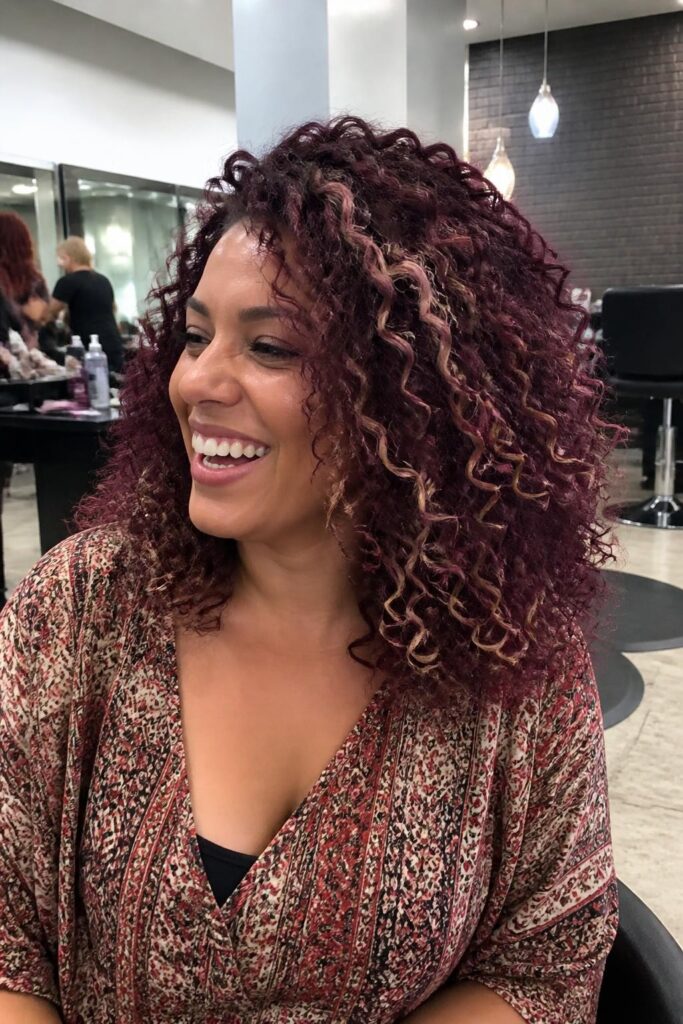 7. Plum base with blonde highlights for curly hair