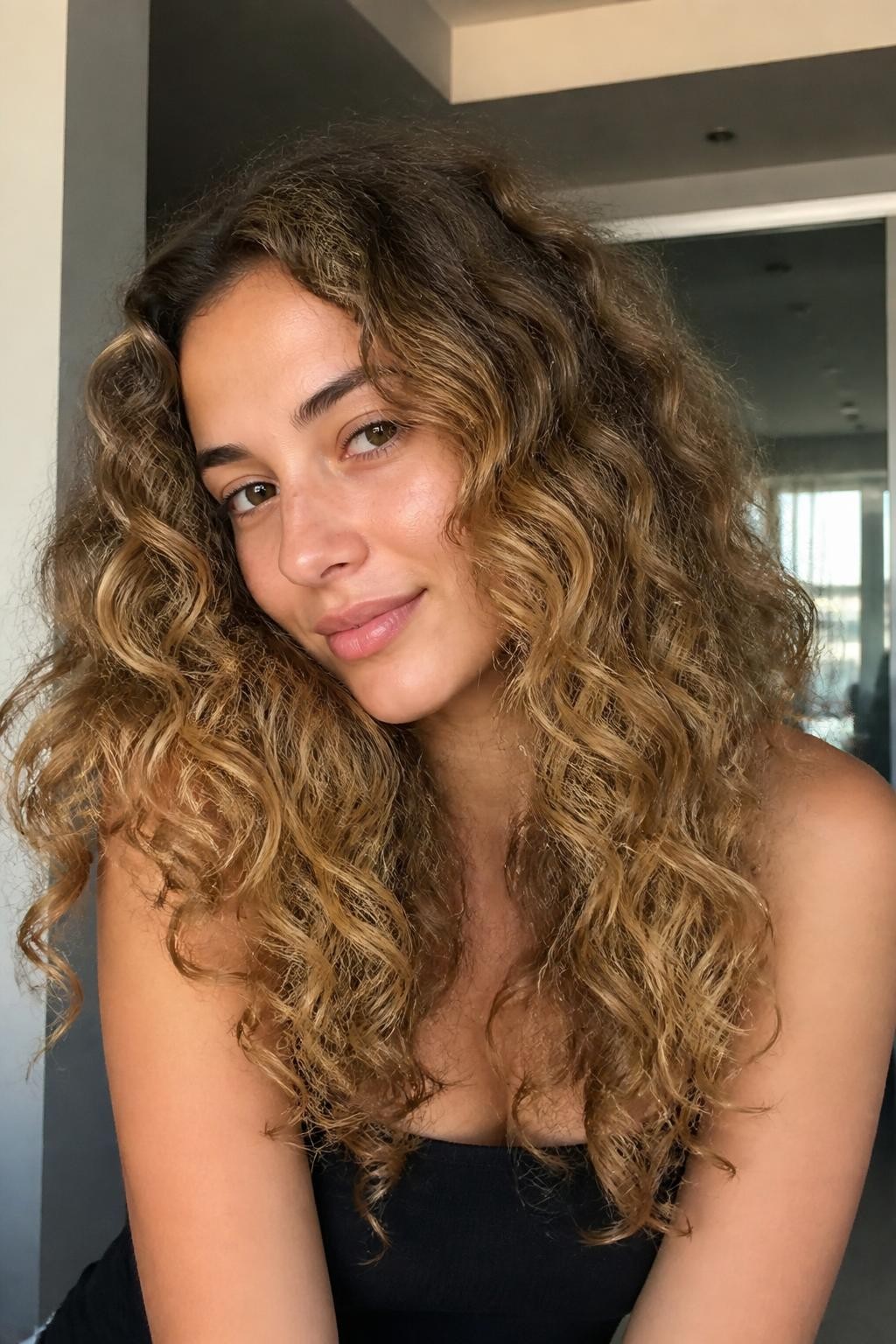 Woman with caramel blonde balayage on curly hair