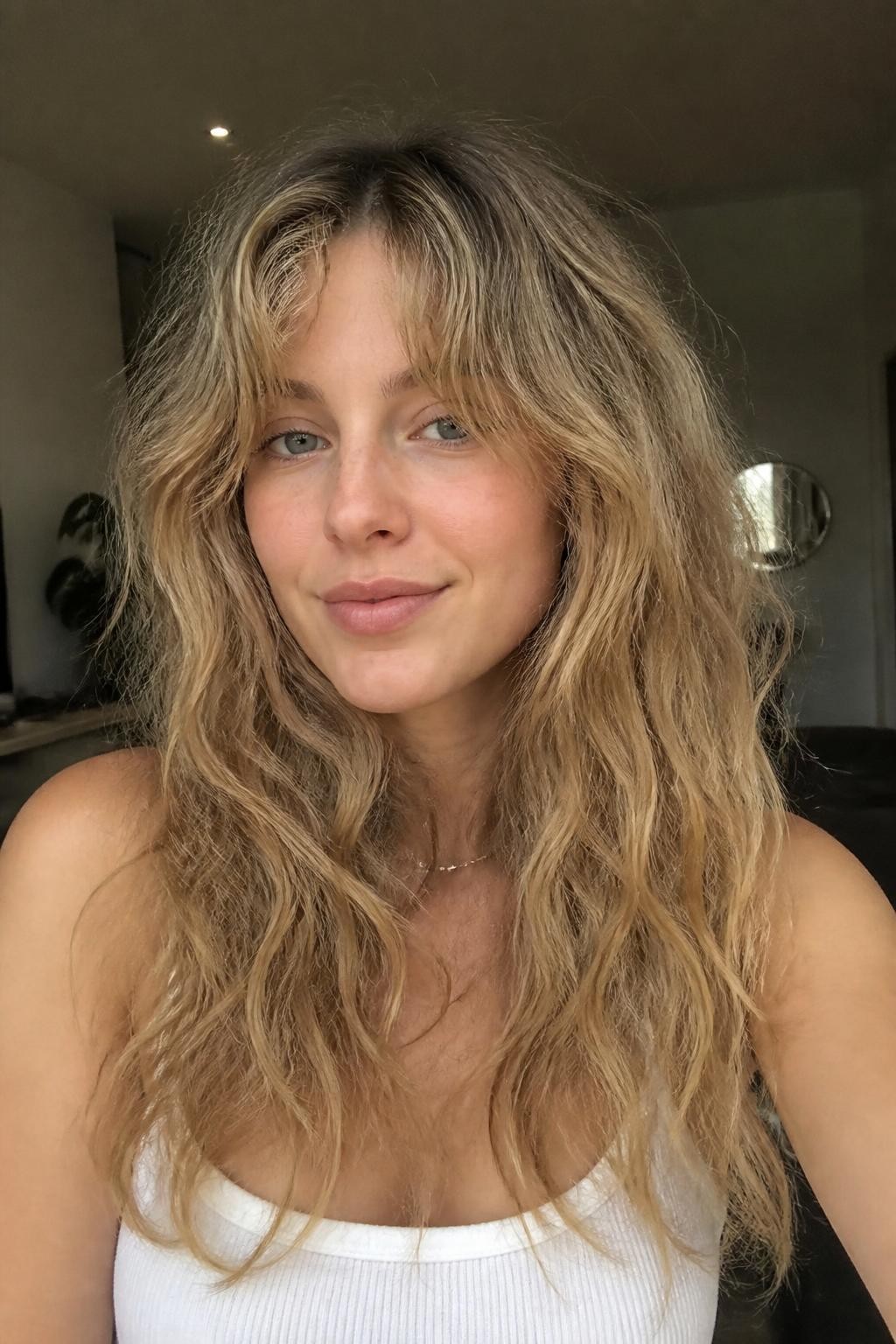 Woman with frizzy wavy hair with curtain bangs, visible texture not sleek