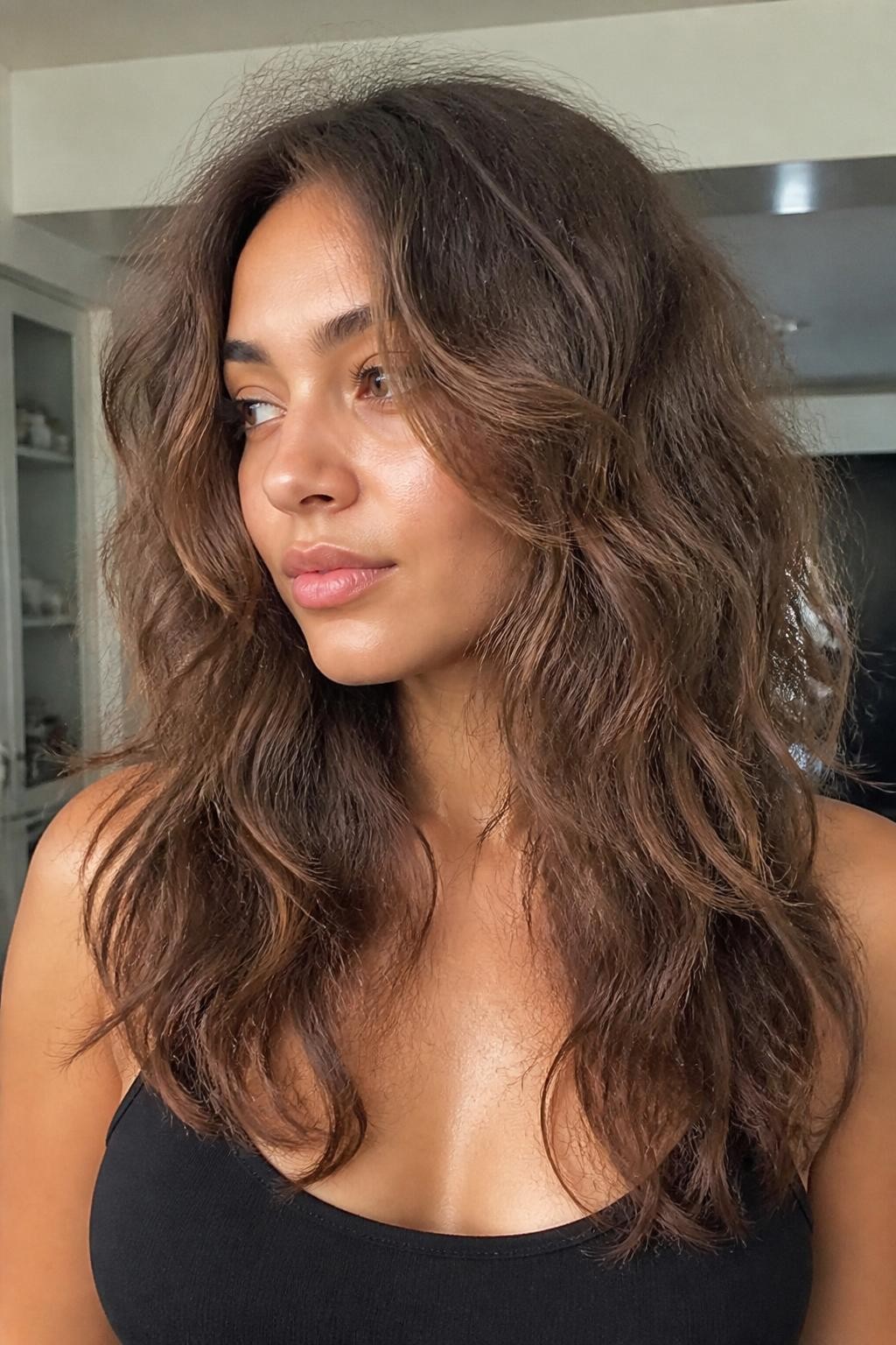 Woman with long layers on frizzy wavy hair past the collarbone with visible frizz
