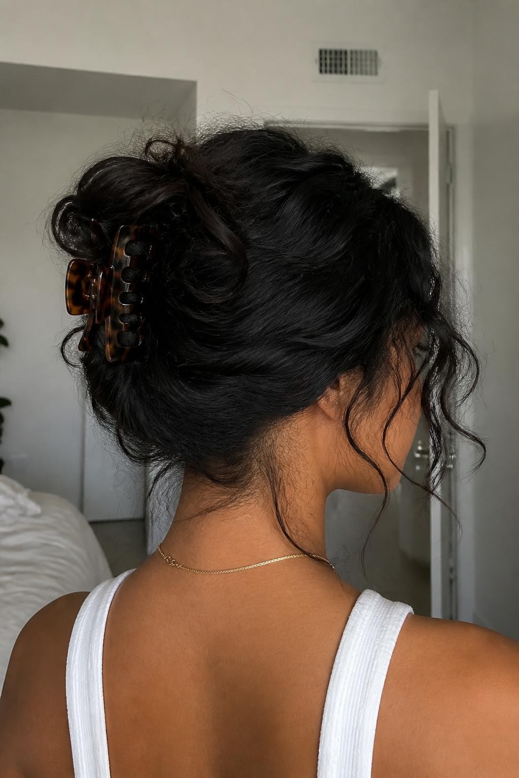Woman with claw clip updo on frizzy wavy hair with loose textured pieces