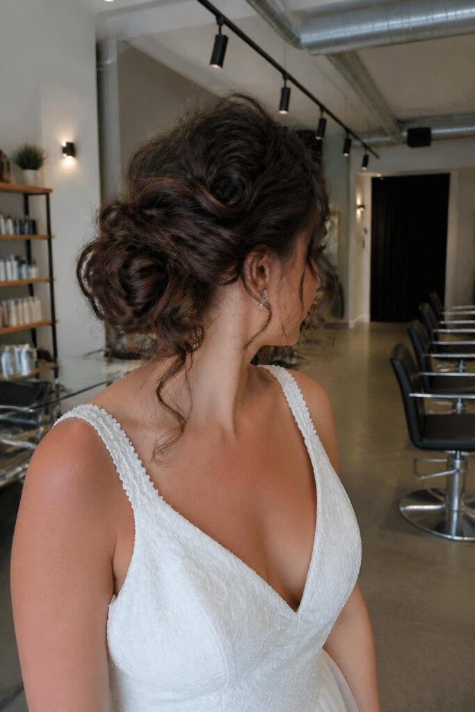 Low messy bun with curly bob tendrils